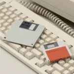 Carcasa naranja junto a un disquete sobre un teclado retro