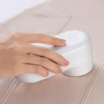 Quitapelusas quitando bolitas de un saco beige